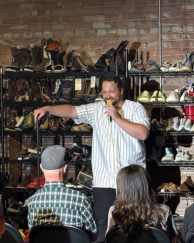 Jaron on stage in front of shelves full of shoes